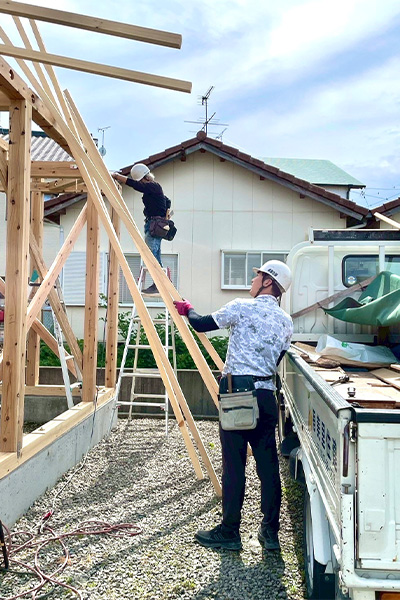 若い家族も参加して農作業小屋の上棟作業を進めている様子